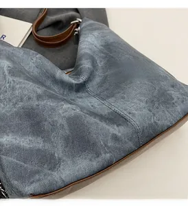 Close-up of grey denim backpack with dark brown leather trim and metallic zipper detail