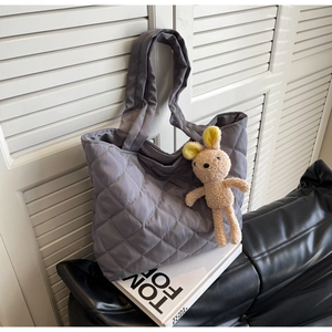 Detail of grey quilted nylon tote bag with plush bunny charm on Tom Ford book