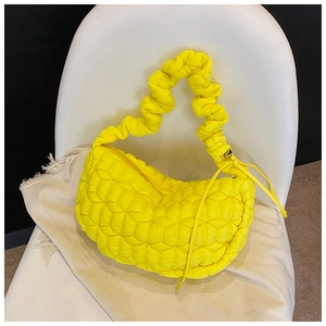 Detailed view of yellow quilted puffer bag with ruffled texture and crescent shape