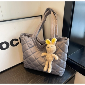 Detail of grey quilted nylon tote bag with a cute plush rabbit charm and wide handle