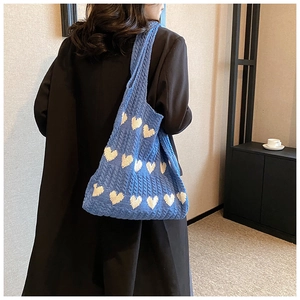 Gros plan d'un cabas tricoté bleu avec motifs de cœurs blancs et texture en maille douce