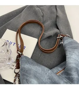Detail of adjustable brown leather strap and denim texture on large capacity bag