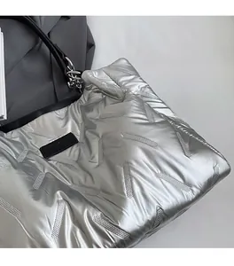 Close-up of silver quilted tote bag featuring metallic finish and black logo detail