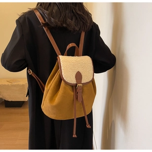 Detail of a brown suede and beige faux fur backpack with leather straps on a model