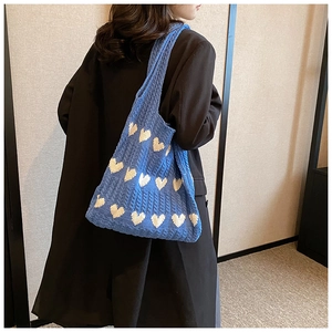 Détail du sac cabas en tricot bleu montrant des motifs de cœurs blancs et texture douce