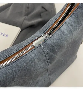 Detailed close-up of smooth silver metal zipper on vintage washed grey denim backpack