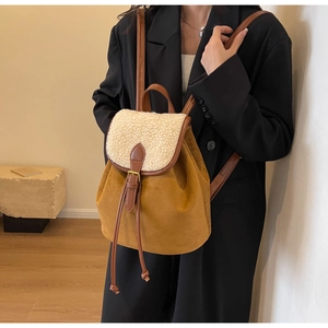 Detail of faux suede backpack with beige faux fur trim and leather strap on a model
