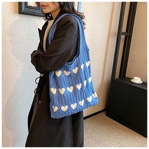 Détail du sac cabas tricoté bleu avec motifs de cœurs et texture côtelée douce au toucher