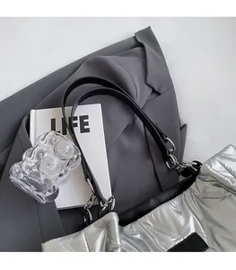 Detail of silver quilted tote bag with black leather strap and metallic ring connectors