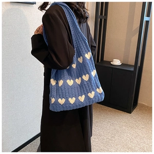 Détail du sac cabas bleu tricoté avec motifs de cœurs et texture en coton doux