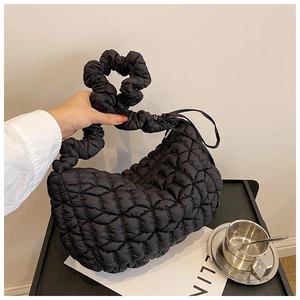 Detail of black puffer bag featuring quilted rhombus pattern and scrunchie handle strap