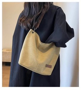 Detailed view of ginger yellow canvas bucket bag with brown leather strap on model