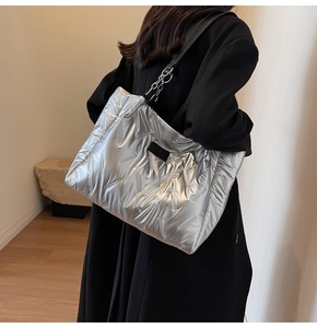 Close-up of silver quilted tote bag with metallic finish and black shoulder strap details