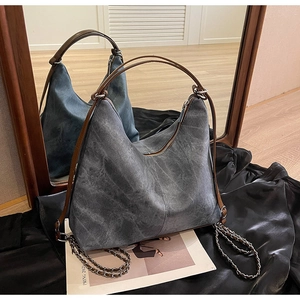 Detail of vintage grey denim hobo bag with metal chain accents on black satin background