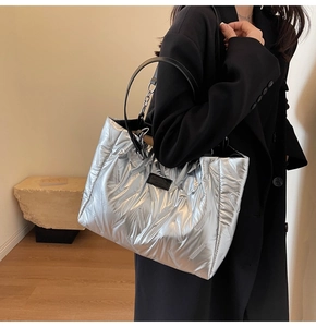 Detailed close-up of a silver quilted puffer tote bag with black leather and chain straps