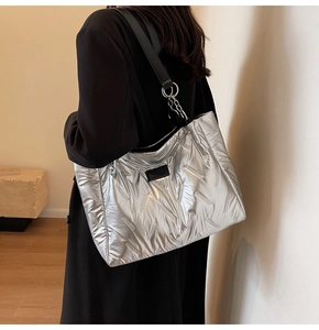 Detail of silver quilted tote bag with black leather strap and silver chain accents