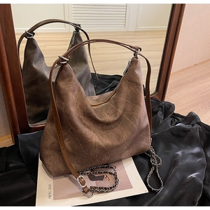 Detail of vintage brown textured leather hobo bag with silver chain on black satin