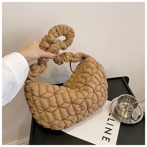 Detail of caramel quilted nylon dumpling bag featuring a ruched handle and metal zipper