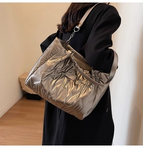 Detail of metallic bronze quilted tote bag with chain strap and fashion label on shoulder