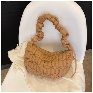 Detailed shot of quilted beige hobo bag texture and ruffled handle on white chair
