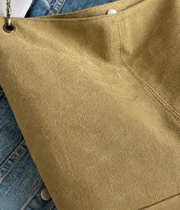 Macro detail of khaki canvas bucket bag showing thick texture and vintage copper eyelets