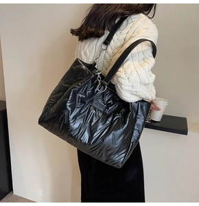 Detail of black quilted tote bag showing metallic nylon texture and chain shoulder strap