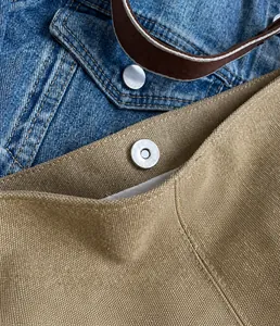 Detail of silver magnetic buckle on khaki canvas bucket bag with light fabric lining