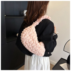 Detailed view of light pink quilted bubble nylon shoulder bag worn by a model