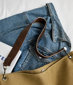Close-up of khaki canvas bucket bag with brown leather strap and contrast stitching