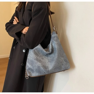 Detail of blue textured hobo bag with silver chain and brown leather shoulder strap