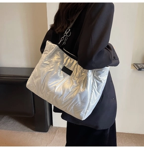 Detailed shot of silver quilted tote bag with metallic texture and chain shoulder strap