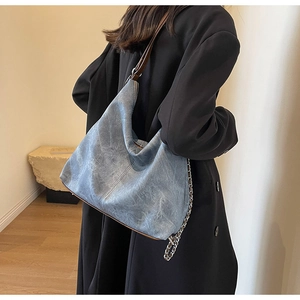 Detail of vintage denim blue large shoulder bag with silver chain and brown leather strap