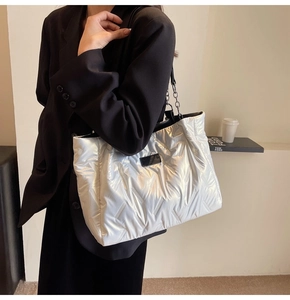 Macro detail of silver quilted tote bag featuring metallic finish and chain strap