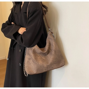 Detailed view of large vintage brown hobo bag with worn texture and chain strap decoration