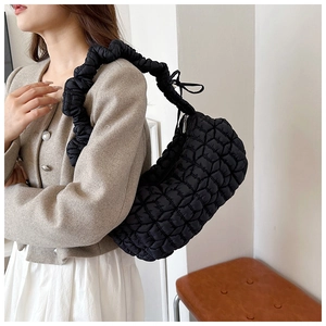 Detail of black quilted dumpling bag with bubble texture and ruffled nylon shoulder strap