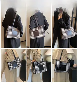 Detail view of large houndstooth tote bag featuring premium leather patch and long straps