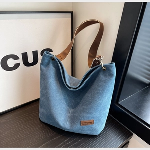 Detail of washed denim canvas tote bag with brown leather strap and fashion label