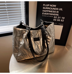 Macro shot of silver puffer tote bag featuring diagonal quilting and metal chain strap
