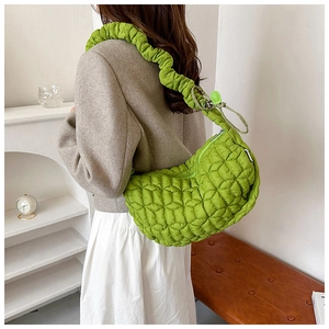 Detail view of neon green quilted nylon dumpling bag with pleated shoulder strap
