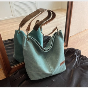 Detail of teal canvas tote bag with leather straps and decorative fashion label