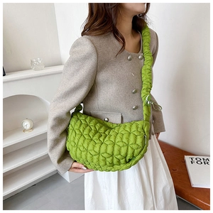Detailed view of avocado green quilted nylon fabric on a crossbody dumpling bag