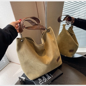 Detail of khaki canvas hobo bag with brown leather strap and logo patch in mirror view