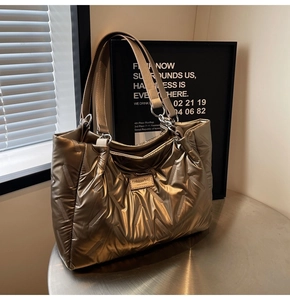 Detail of metallic gold quilted tote bag with fashion brand tag on a stainless steel table