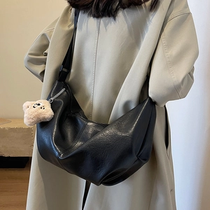 Black crescent dumpling bag with pleats, adjustable strap and plush bear charm