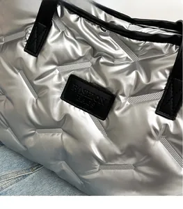 Détail du tissu métallisé argenté matelassé et du logo noir sur le sac à main chic