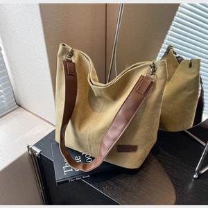 Detailed close-up of a mustard canvas hobo bag with a leather fashion tag and wide strap