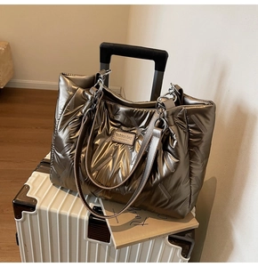 Metallic bronze quilted tote bag showing large capacity storage on a white suitcase