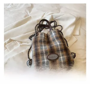 Detail der Tweed-Beuteltasche mit Karomuster, Logo-Plakette und Ketten-Schultergurt