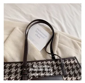 Detail of adjustable leather strap and metal buckle on houndstooth tote bag