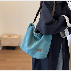 Detail of teal canvas hobo bag with brown leather strap and fashion leather patch